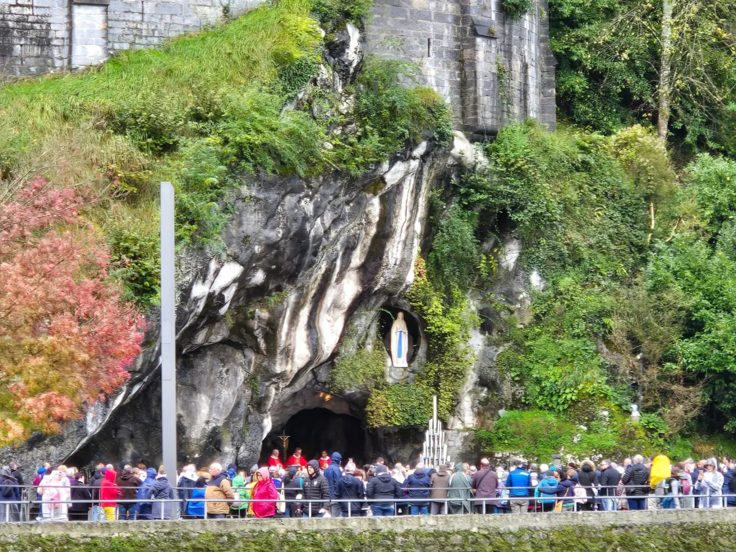 A group of people standing around in front of a rock wall.